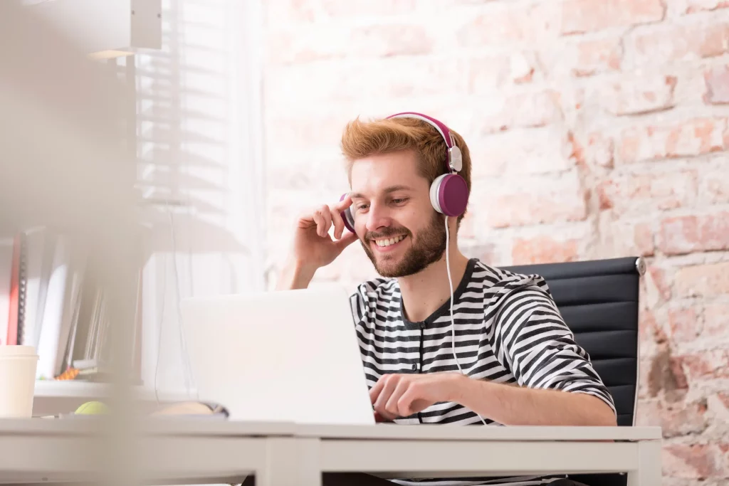 Lächelnder Ausbildungsbeauftragter sitzt mit einem Headset vor seinem Laptop